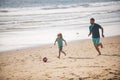 Father and son play soccer or football on the beach on summer family holidays. Dad and child playing outdoor. Royalty Free Stock Photo