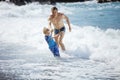 Father and son playing on the beach in rough water Royalty Free Stock Photo