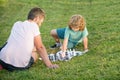 father and son playing chess on grass in park. fathers day. happy family. parenthood