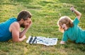 Father and son playing chess lying on grass at lawn park. Fathers Day, love family, parenthood, childhood concept. Royalty Free Stock Photo