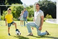 Father and son playing football in park on a sunny day