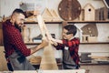 Father and son playing knights with wooden DIY swords at carpenter workshop Royalty Free Stock Photo