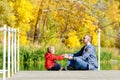 Father and son are playing on the pier. Autumn, sunny. Side view Royalty Free Stock Photo