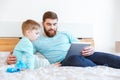 Father and son playing with tablet on bed Royalty Free Stock Photo