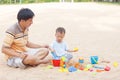 Father and son playing together, cute little Asian toddler boy child sitting & playing children`s beach toys bucket and spade on s Royalty Free Stock Photo