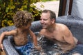 Father and son playing together in a hot tub outdoors. Laughing and having fun in a warm spa in the back yard Royalty Free Stock Photo