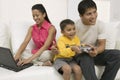 Father and son playing video game, mother using pc Royalty Free Stock Photo