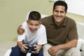 Father with Son Playing Video Game on sofa in living room portrait Royalty Free Stock Photo