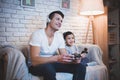 Father and son are playing video games on tv at night at home. Royalty Free Stock Photo