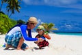 Father and son playing with water guns on the beach