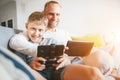 Father and son portrait with electronic devices playing. Sitting at home in cozy atmosphere