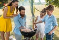 Father and son preparing meat on charcoal barbecue grill during