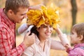 Father and son put yellow fallen leaves on mother head. Happy family is in autumn city park. Children and parents. They posing, sm Royalty Free Stock Photo