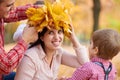 Father and son put yellow fallen leaves on mother head. Happy family is in autumn city park. Children and parents. They posing, Royalty Free Stock Photo