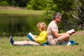 Father and son reading book in park, man encourages boy to knowledge, family education. Father and child read book Royalty Free Stock Photo