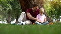 Father and son reading book in park, man encourages boy to knowledge, family Royalty Free Stock Photo