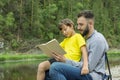 Father and son reading book in park in summer day Royalty Free Stock Photo