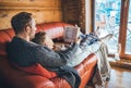 Father and son reading book together lying on the cozy sofa in warm country house. Reading to kids conceptual image
