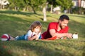 father and son relax on grass in park learning to draw, tutorship