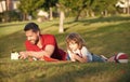 father and son relax on grass in park learning to draw, tutorship