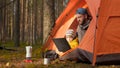 Father and son relaxing together in nature in the spring forest, sitting in an orange tent and watching videos together Royalty Free Stock Photo