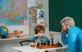 Father and son relaxing together. Nice concentrated little boy sitting at the table and playing chess with his father Royalty Free Stock Photo