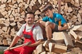 Father and son resting on pile of chopped wood