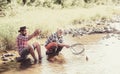 Father with son on the river enjoying fishing holding fishing rods. Happy family concept - father and son together.