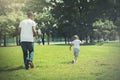 Father and son running and chasing each other in green park