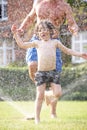 Father And Son Running Through Garden Sprinkler Royalty Free Stock Photo