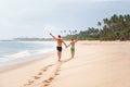 Father and son in Santa`s hats run on perfect sand beach on trop