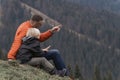 Father and son sit on hillside on the forest background. Trekking and hiking with children. Weekend hike in mountains