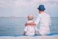 Father and son sit on the sea pier and look on the ship on horizont line Royalty Free Stock Photo