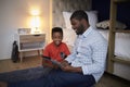 Father With Son Sitting In Bedroom Playing Game On Digital Tablet Together Royalty Free Stock Photo