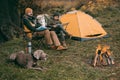 Father and son sitting on camp-chairs at bonfire