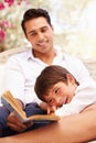 Father And Son Sitting In Garden Reading Book Together Royalty Free Stock Photo