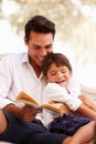 Father And Son Sitting In Garden Reading Book Together Royalty Free Stock Photo