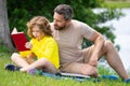 Father and son sitting on green grass in garden and reading book together. Happy family reading book together in green Royalty Free Stock Photo