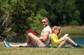 Father and son sitting on green grass in garden and reading book together. Happy family reading book together in green Royalty Free Stock Photo