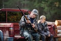 Father and son sitting in a pickup truck after hunting in forest. Dad showing boy mechanism of a shotgun rifle. Royalty Free Stock Photo