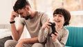 Father and Son Sitting and Playing on Console.