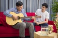 Father and son sitting playing guitar, singing To build a family relationship. happily In the living room at their home Royalty Free Stock Photo