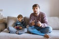 Father And Son Sitting On Sofa In Lounge Playing Video Game Royalty Free Stock Photo