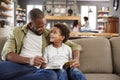 Father And Son Sitting On Sofa In Lounge Reading Book Together Royalty Free Stock Photo