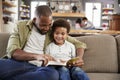 Father And Son Sitting On Sofa In Lounge Reading Book Together Royalty Free Stock Photo