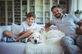 Father and son sitting on sofa with pet dog in living room Royalty Free Stock Photo