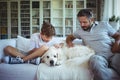 Father and son sitting on sofa with pet dog in living room Royalty Free Stock Photo