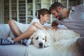 Father and son sitting on sofa with pet dog in living room Royalty Free Stock Photo