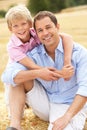 Father And Son Sitting On Straw Bales In Harvested Royalty Free Stock Photo