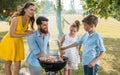 Father and son preparing meat on charcoal barbecue grill